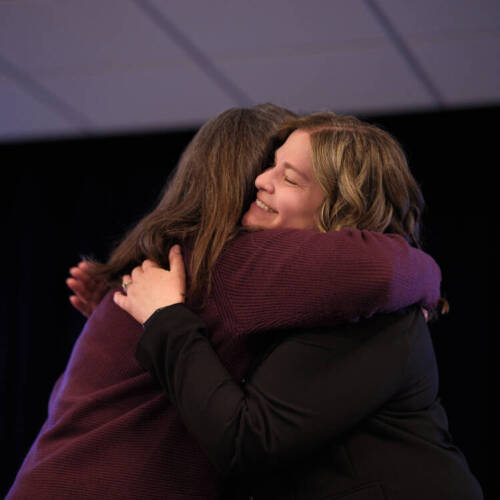 two women hugging on stage